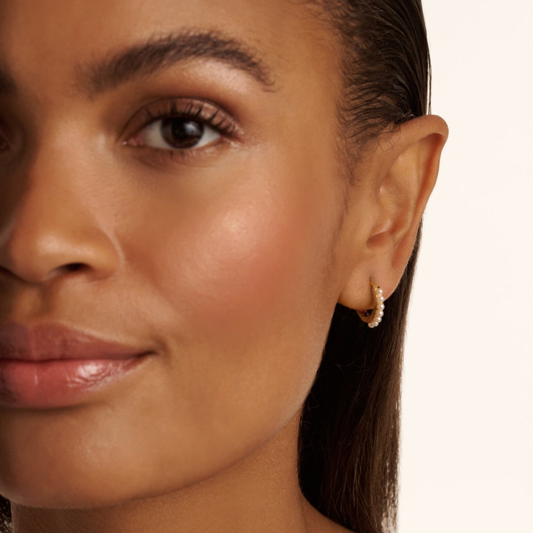 Close-up of a woman's face with a neutral background WEARING TED BAKER EARRINGS