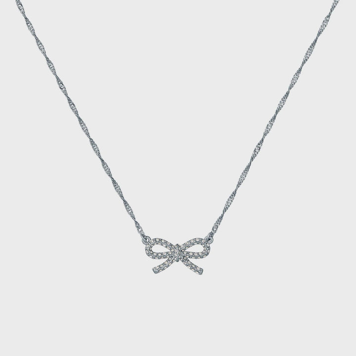 Silver bow-shaped necklace on a light gray background