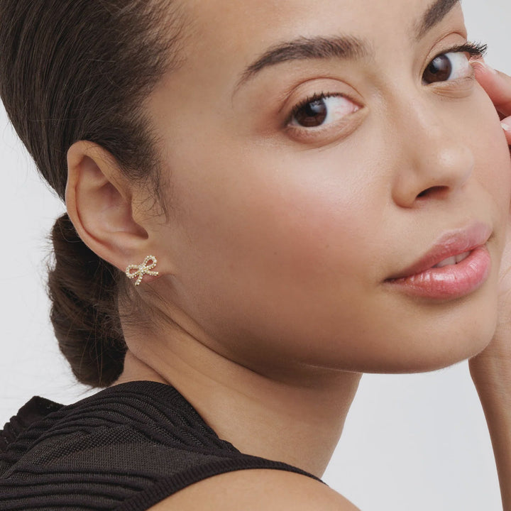 Close-up of a woman wearing a delicate earring with a plain background