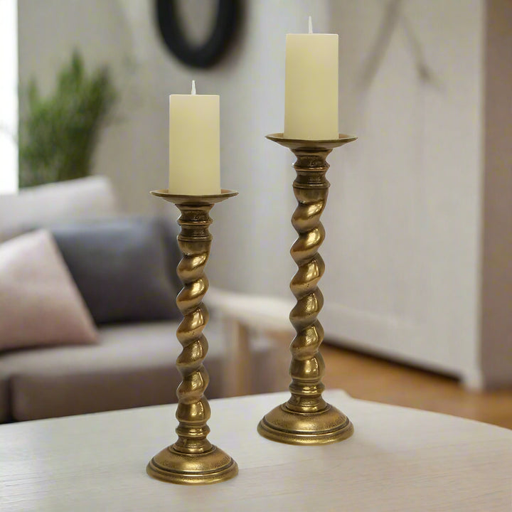 Two gold candle holders with candles on a white background