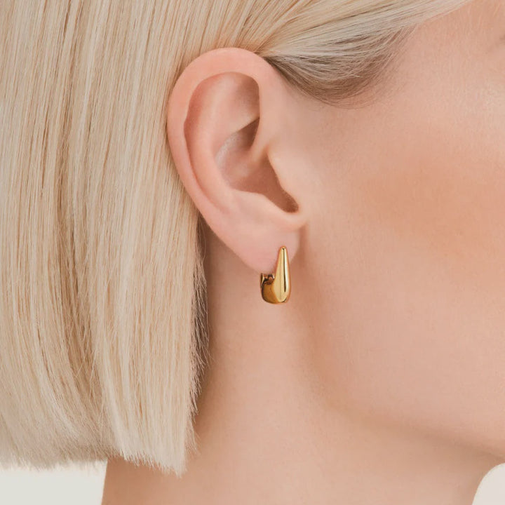 Gold hoop ted baker earring worn by a person with blonde hair.