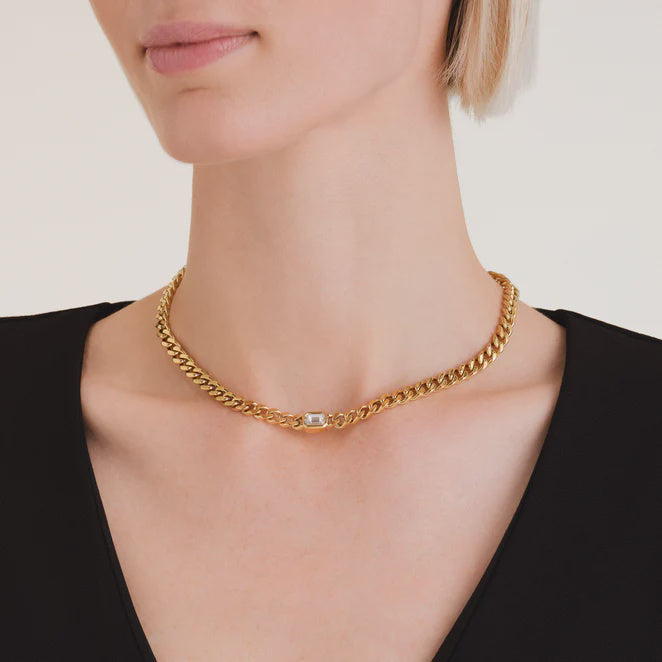 Gold chain ted baker necklace worn by a person on a plain background