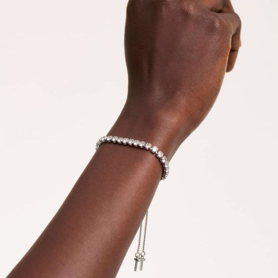 Hand wearing a silver ted baker bracelet on a plain background