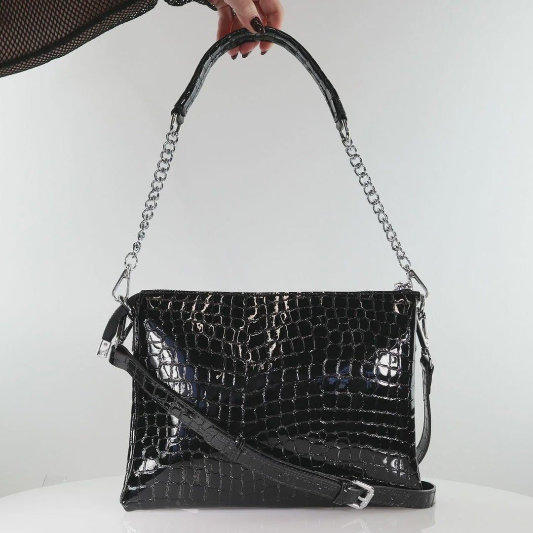 Black crocodile-patterned handbag with a chain strap on a white surface.