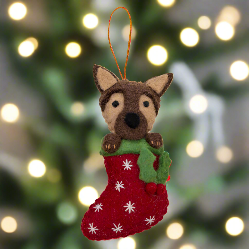 Felt dog ornament in a red stocking with white snowflakes on a white background
