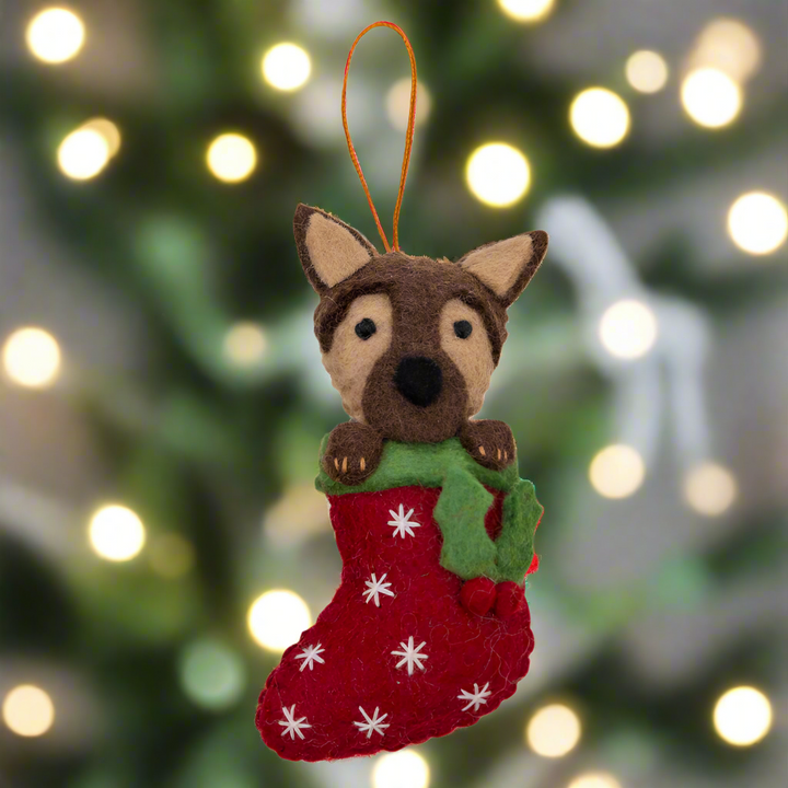 Felt dog ornament in a red stocking with white snowflakes on a white background