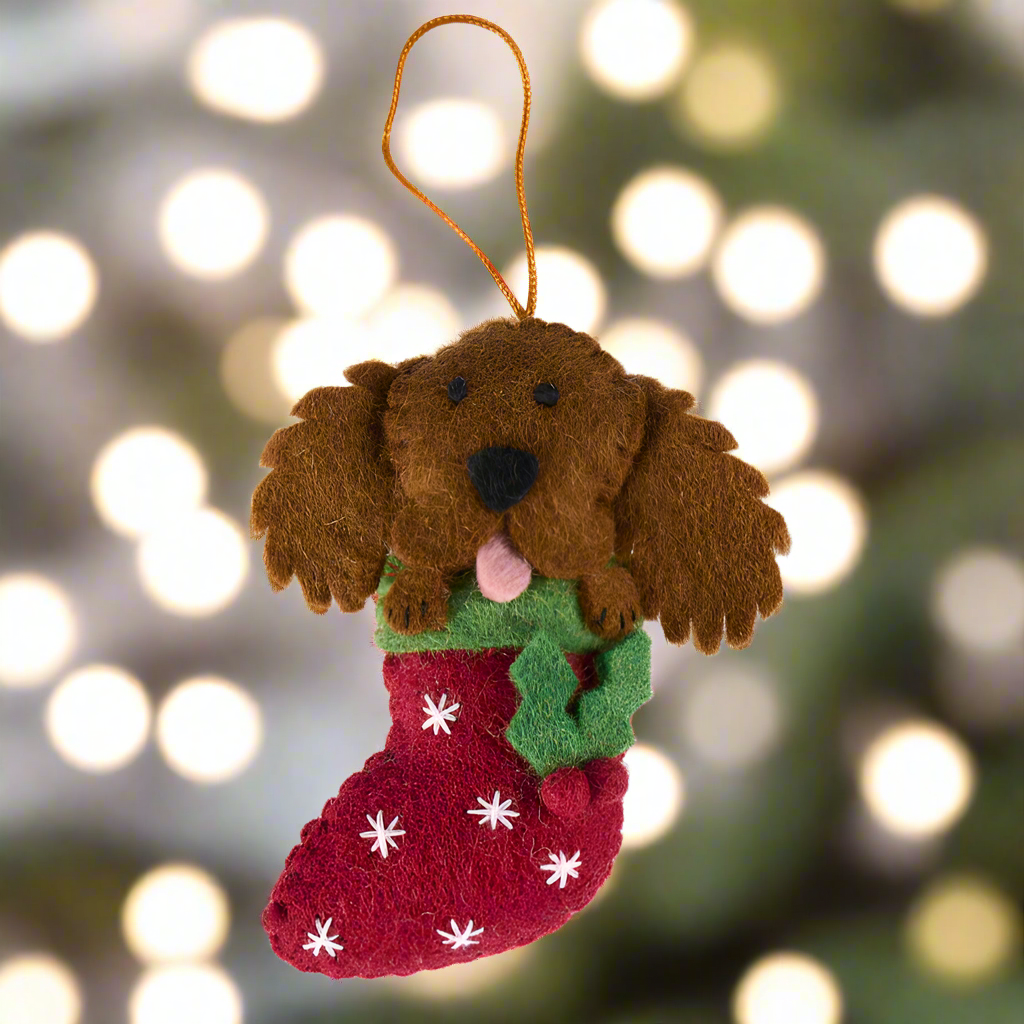 Felt dog ornament in a red stocking with white snowflakes on a white background