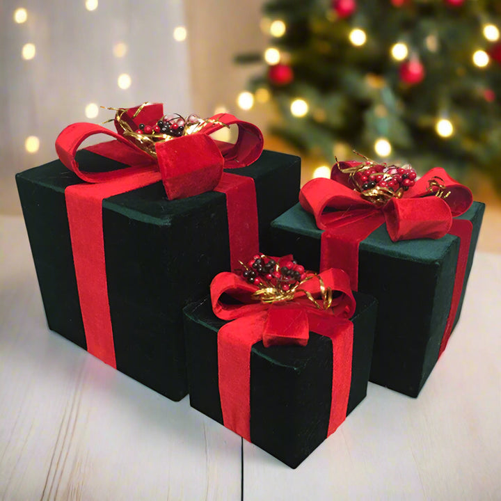 Three green velvet gift boxes with red bows on a white background
