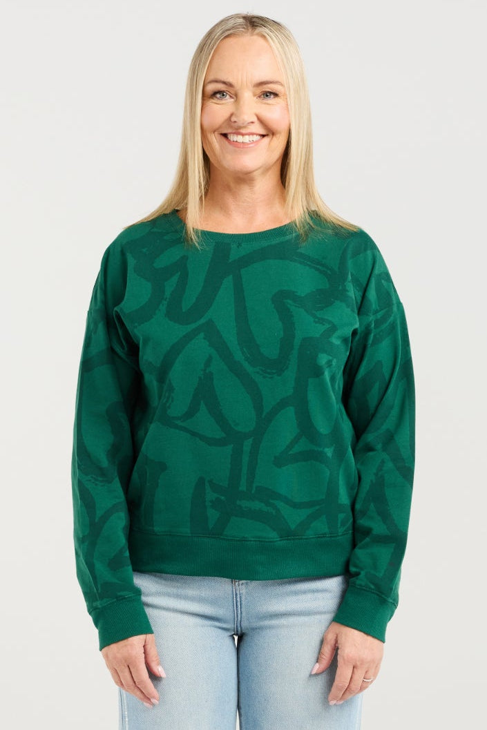 Woman wearing a green sweater and light blue jeans on a white background