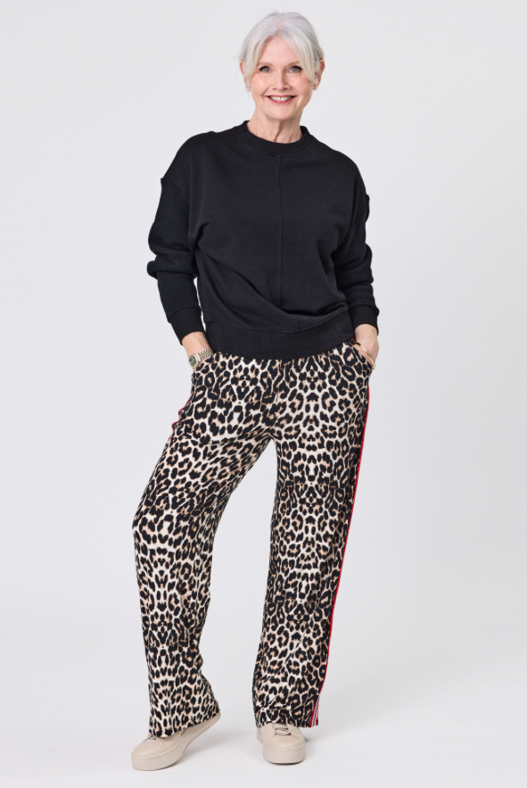 Person wearing a black sweater and leopard print pants on a white background