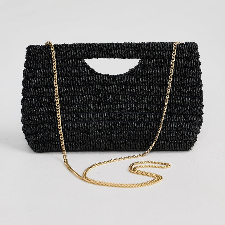 Black woven handbag with a gold chain strap on a light gray background