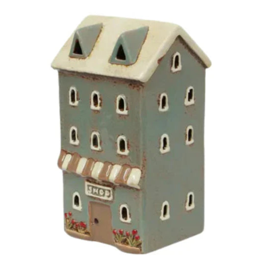 Decorative ceramic house with a shop sign on a white background