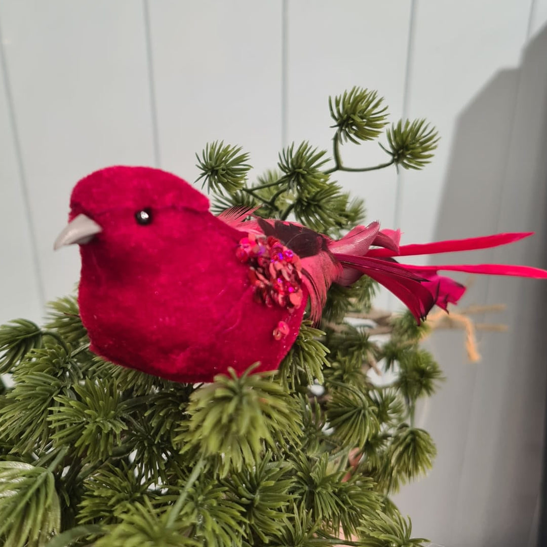 Red bird ornament on a branch against a white paneled wall
