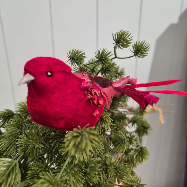 Red bird ornament on a branch against a white paneled wall
