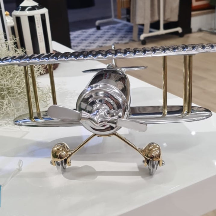 Metallic airplane model on a white surface with clothing in the background