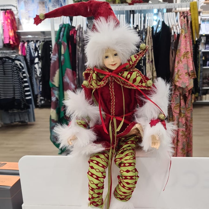 Decorative elf figurine in a store setting with clothing racks in the background