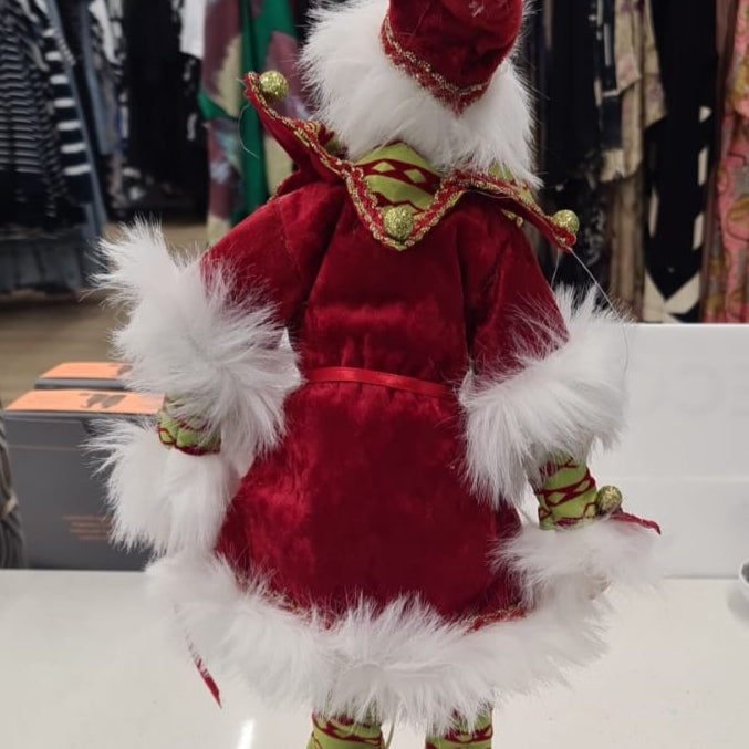 Decorative elf figure with red and white fur on a counter in a store setting
