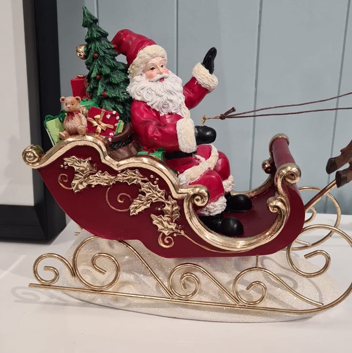 Decorative figure of Santa Claus in a sleigh with a Christmas tree on a white background
