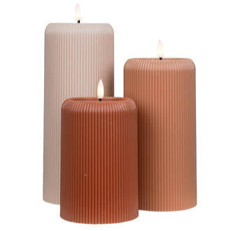 Three ribbed candles in terracotta and beige colors on a white background