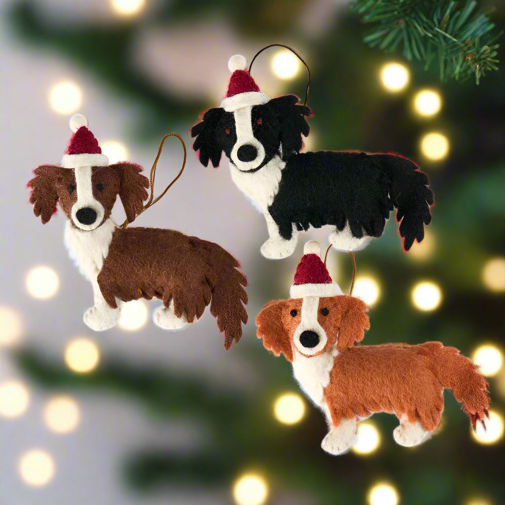 Three dog-shaped Christmas ornaments with Santa hats on a white background
