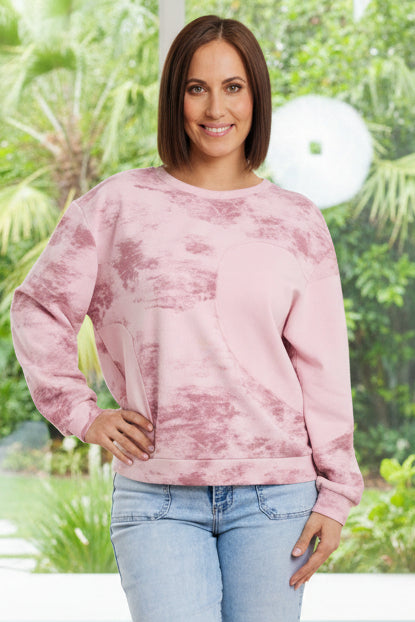 Woman wearing a pink tie-dye sweatshirt and light blue jeans on a white background