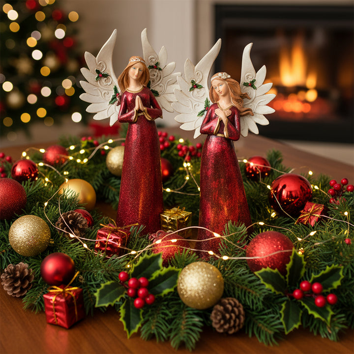 Two christmas decorations, angel figurines with red dresses and white wings on a white background