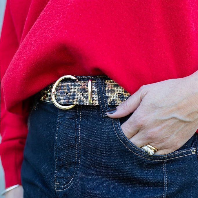 Person wearing a red sweater and blue jeans with a patterned belt.