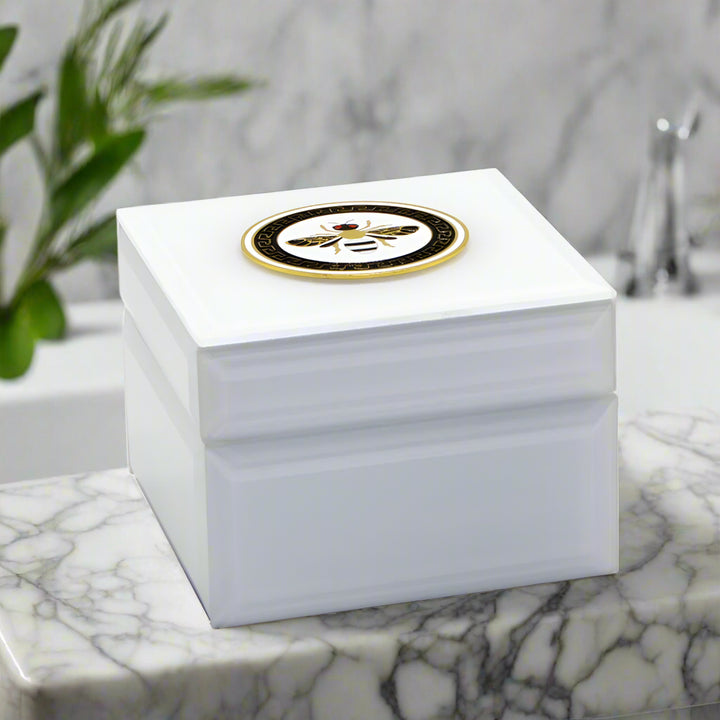 White jewelry box with a gold and black bee emblem on a white background