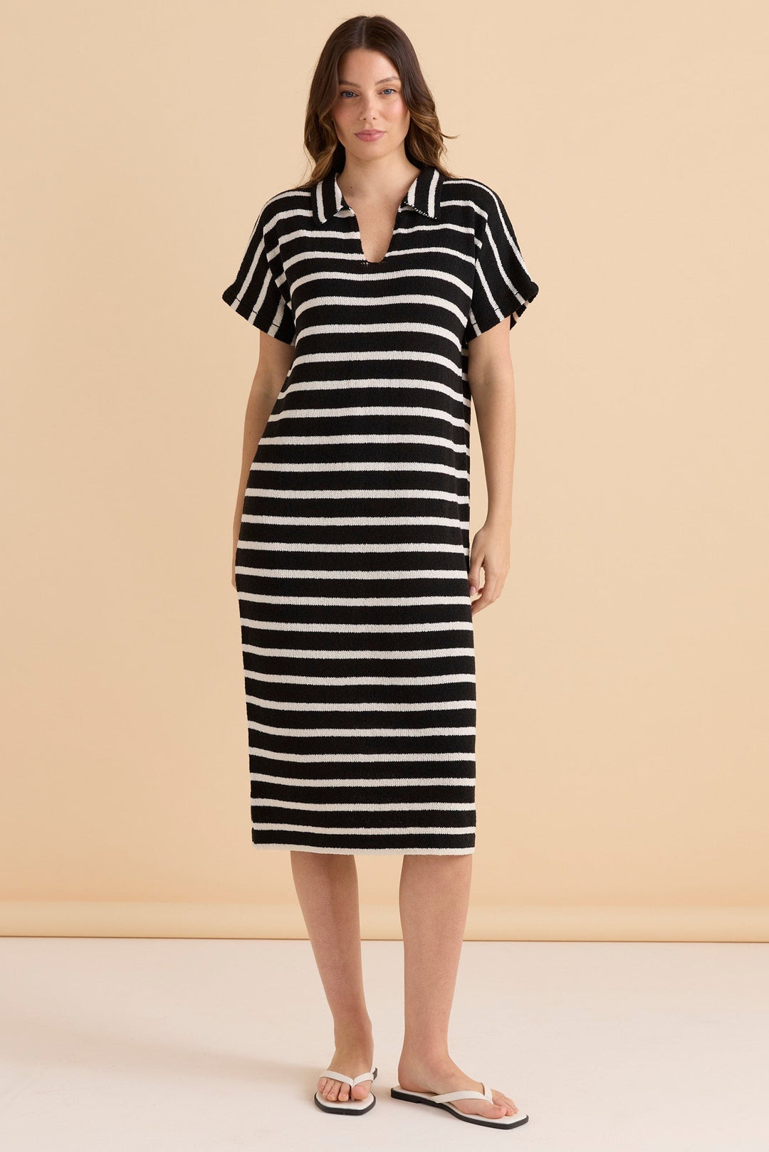 Woman wearing a black and white striped betty basics knit bradford dress dress against a beige background