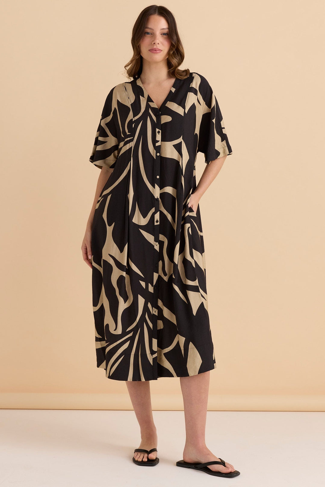 Woman wearing a black and beige patterned betty basics camille dress shirt dress against a beige background