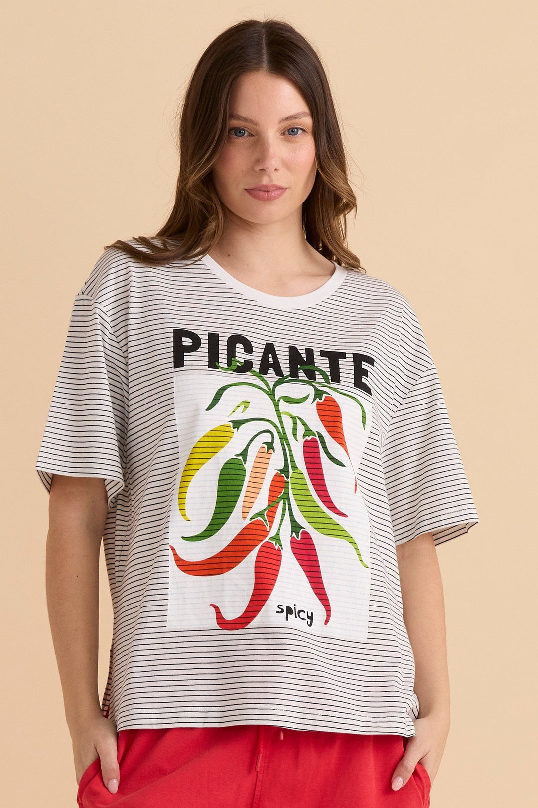 Woman wearing a striped betty basics t-shirt with a graphic chilli design and text on a beige background