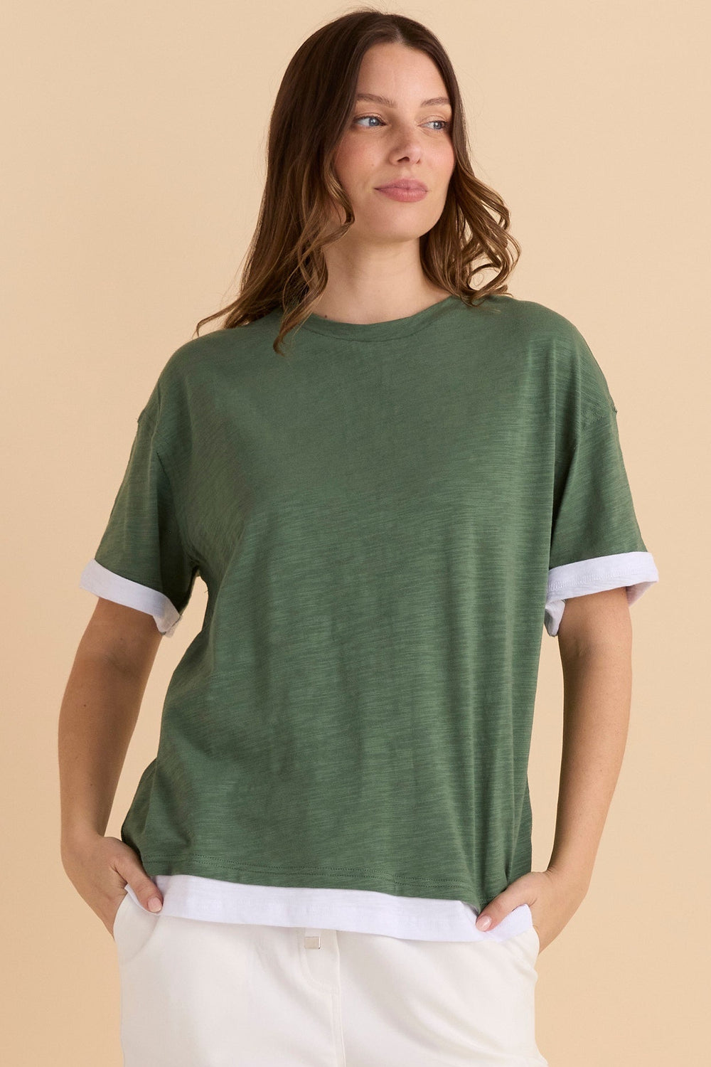 Woman wearing a green t-shirt with white trim on a beige background