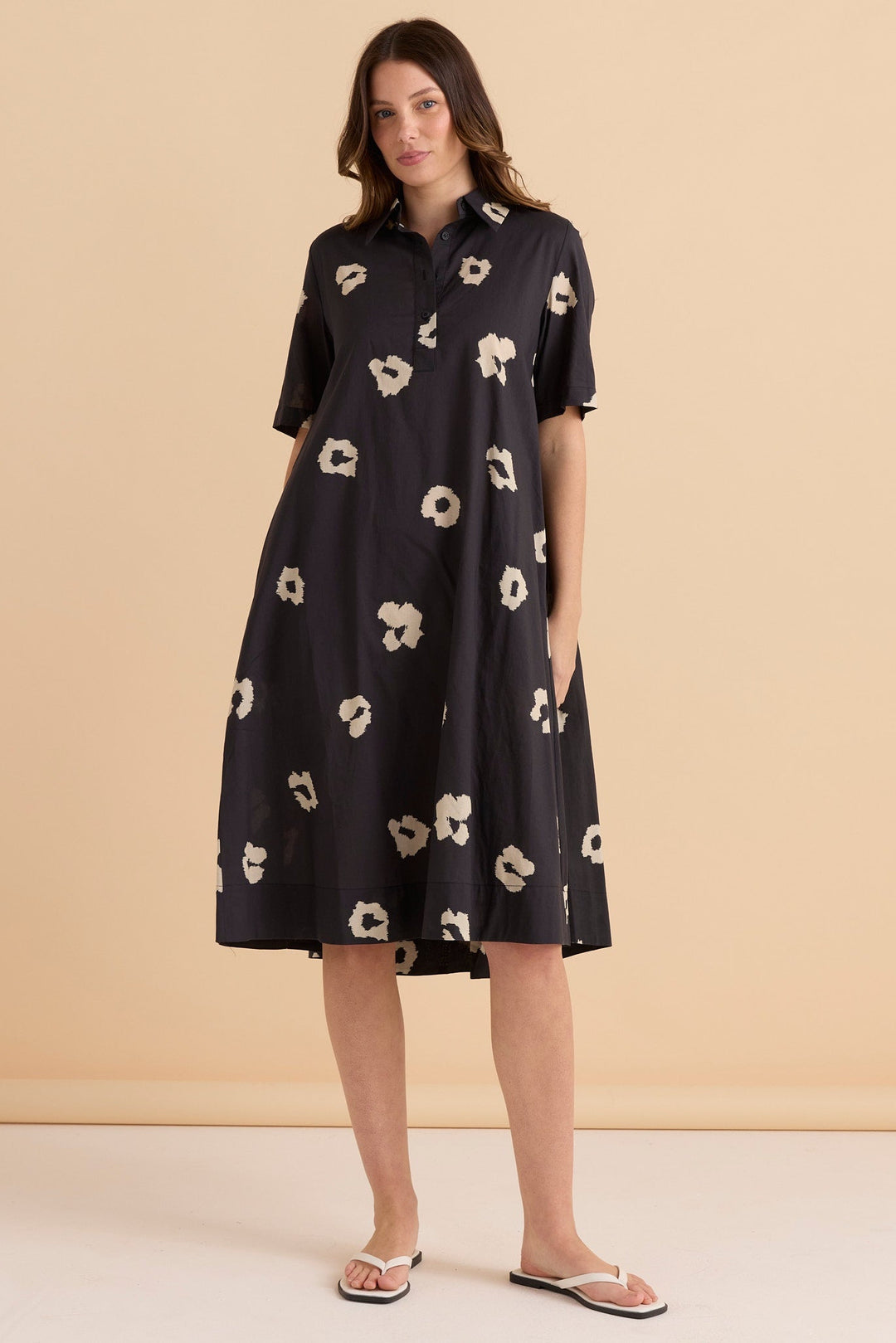 Woman wearing a black betty basics savannah dress with cream leopard pattern against a beige background