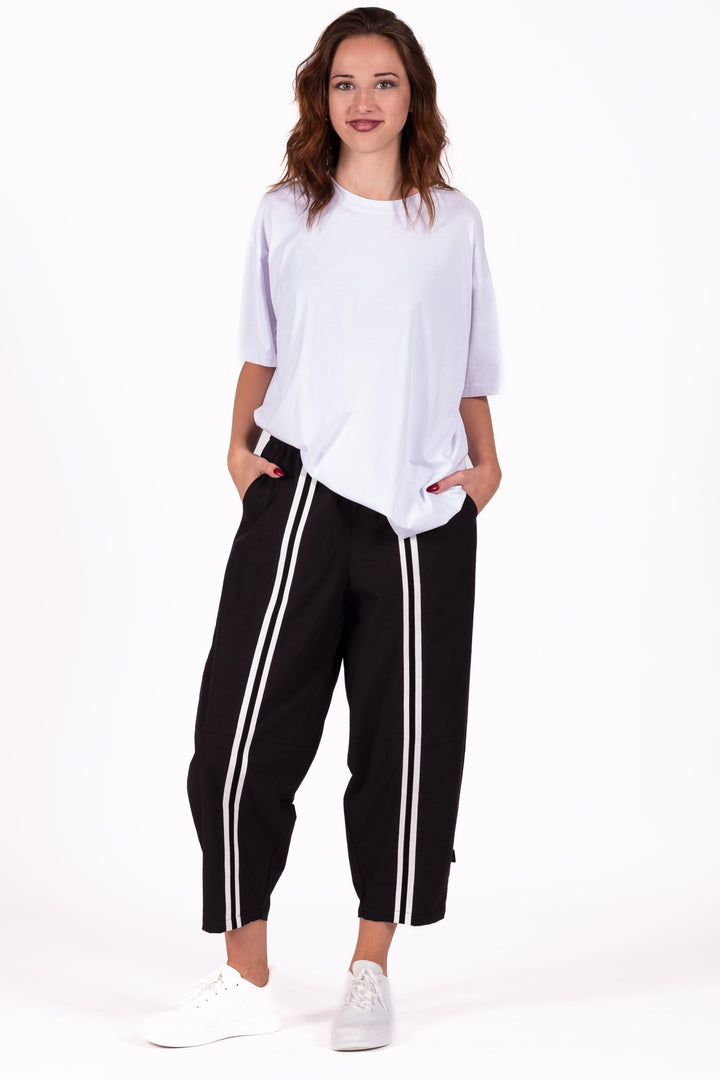 Woman wearing a white top and black pants with white stripes on a white background