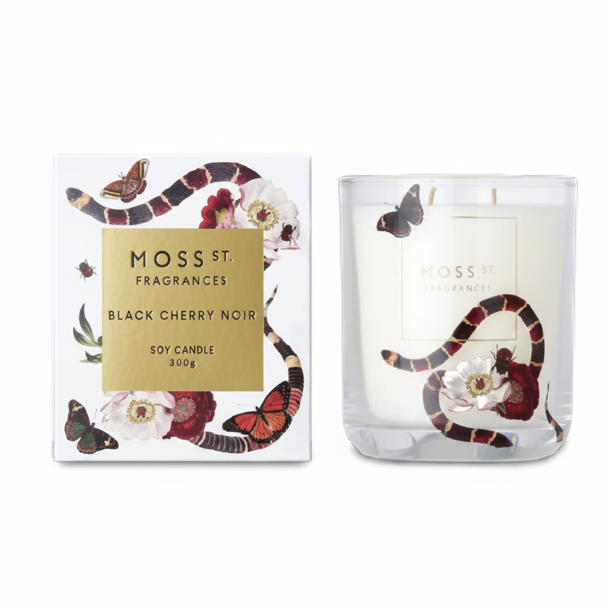 Moss St. Fragrances Black Cherry Noir soy candle shown next to its white packaging box, both decorated with a black and red snake, butterflies, and cherry blossom flowers.