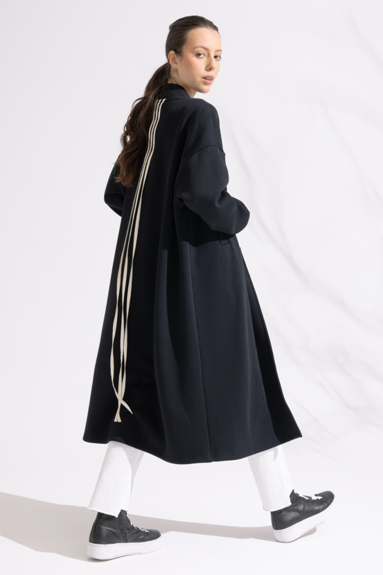 Person wearing a long black coat on a white background