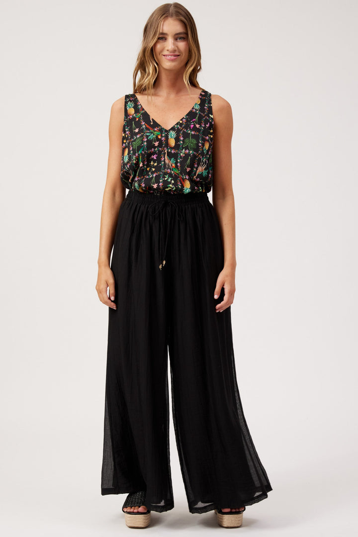 A woman modeling lack palazzo pants and a patterned singlet top