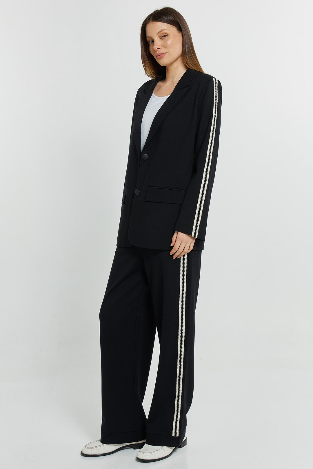 Woman wearing a black suit with white stripes on a white background