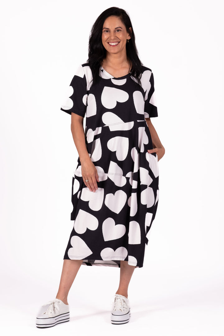 Woman wearing a black dress with white heart patterns on a white background