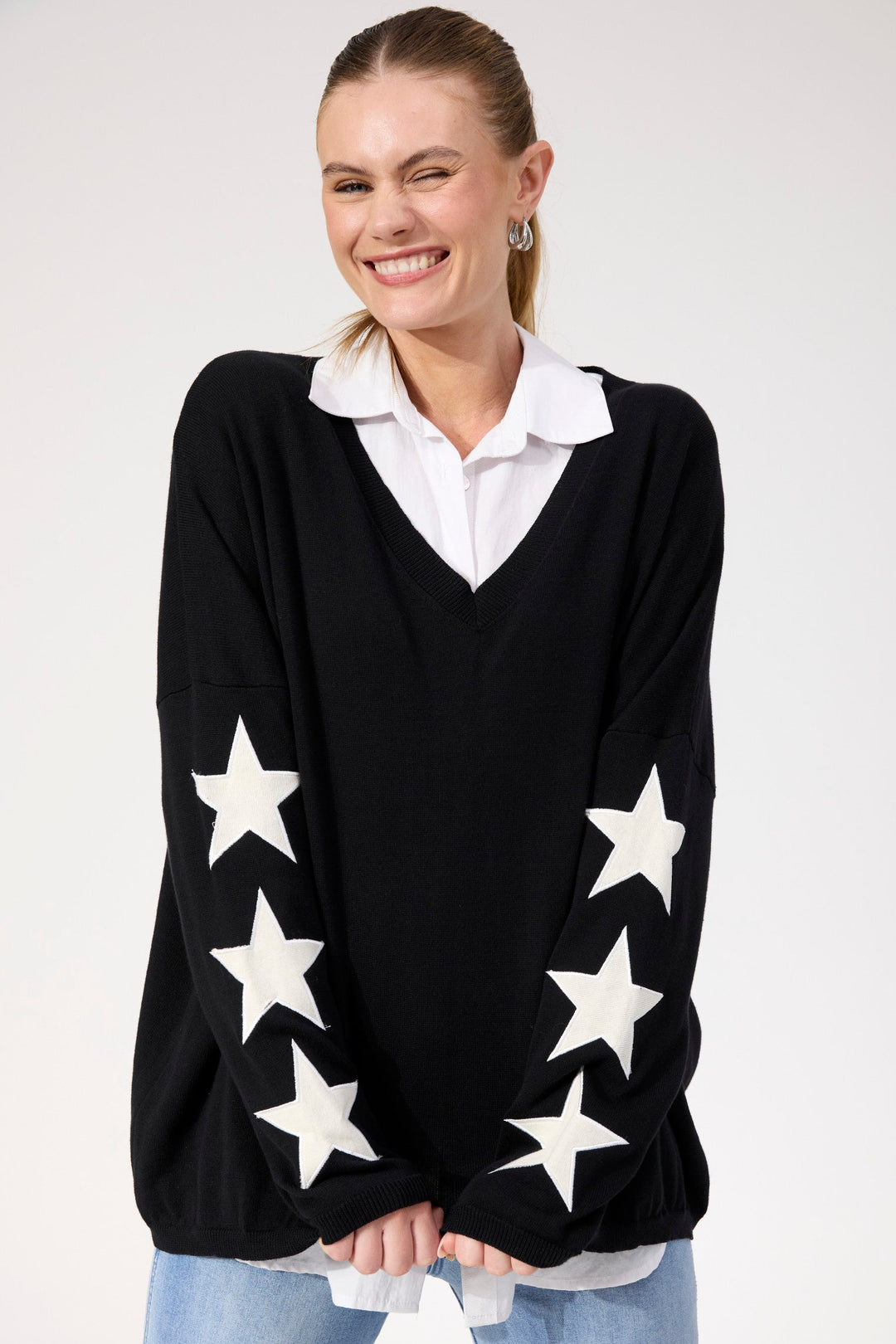 Woman wearing a black sweater with white star patterns on a white background