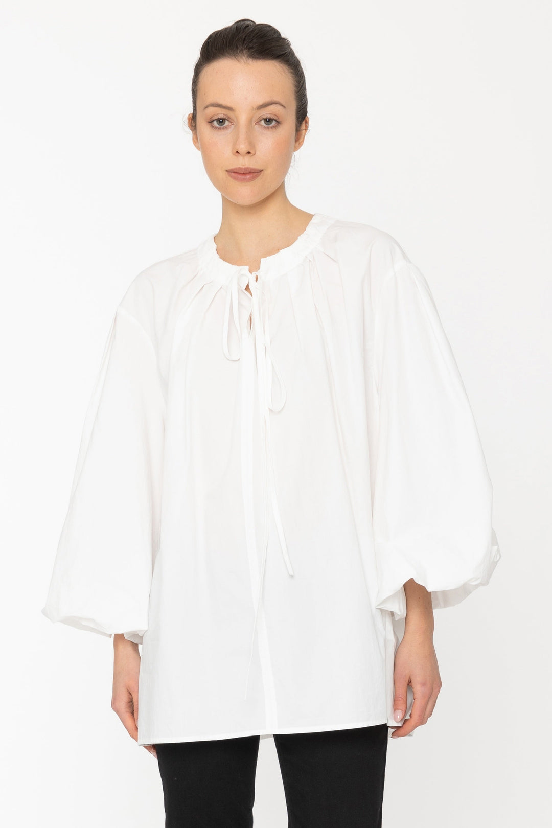 Person wearing a white blouse and black pants on a white background