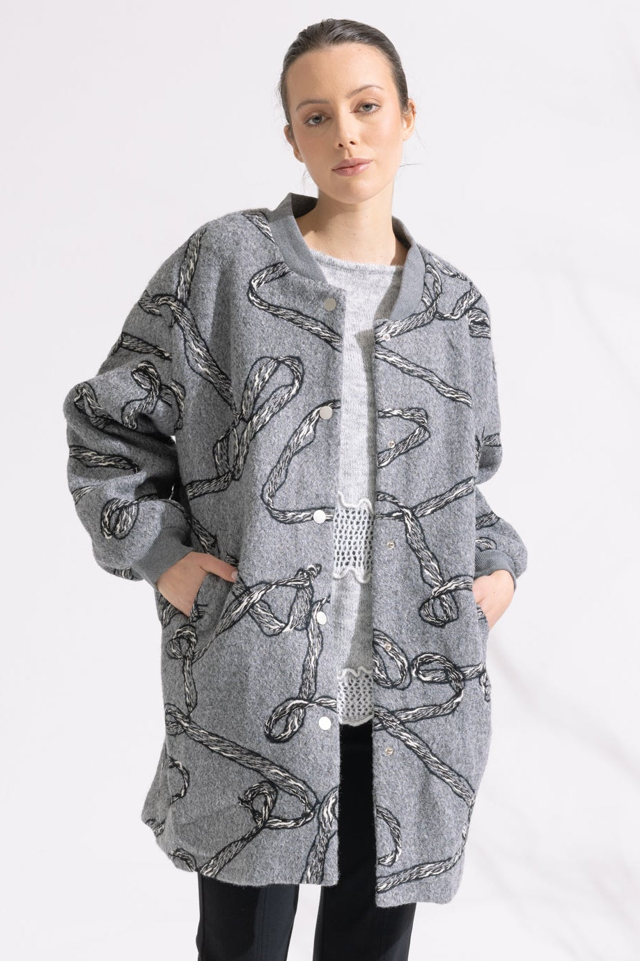 Person wearing a patterned gray coat on a white background