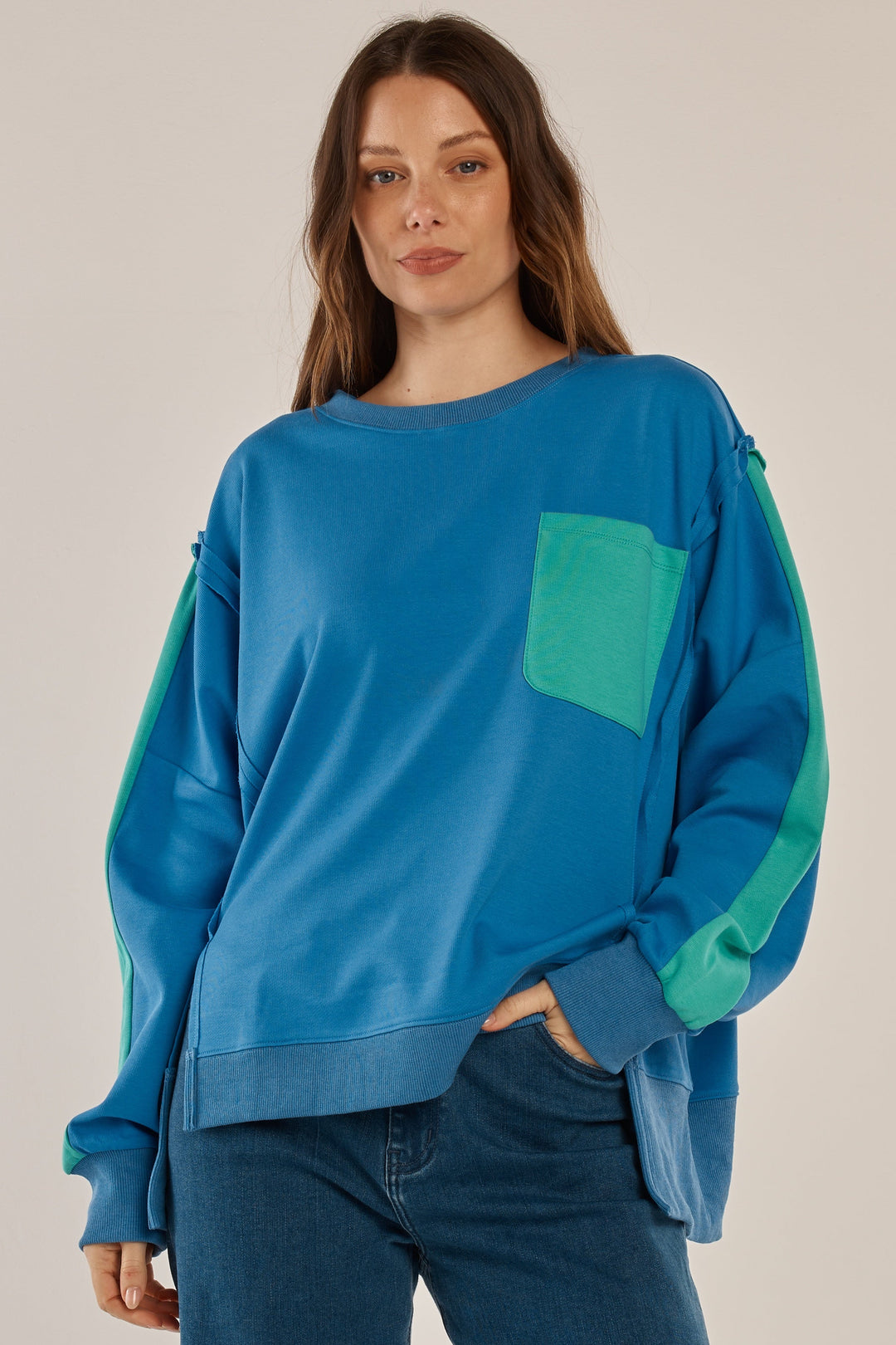 Woman wearing a blue sweater with green accents on a plain background