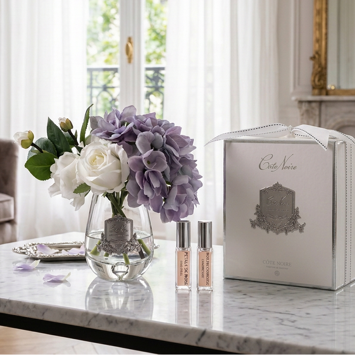 Perfume set with flowers and packaging on a white table in luxury room