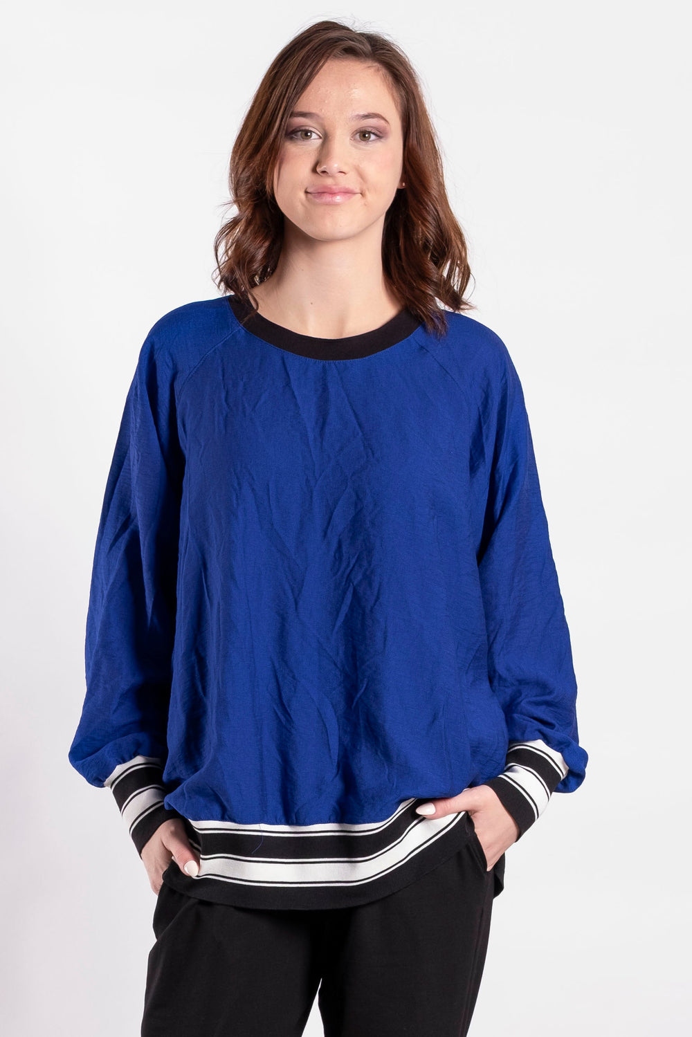 Person wearing a blue sweater and black pants on a white background