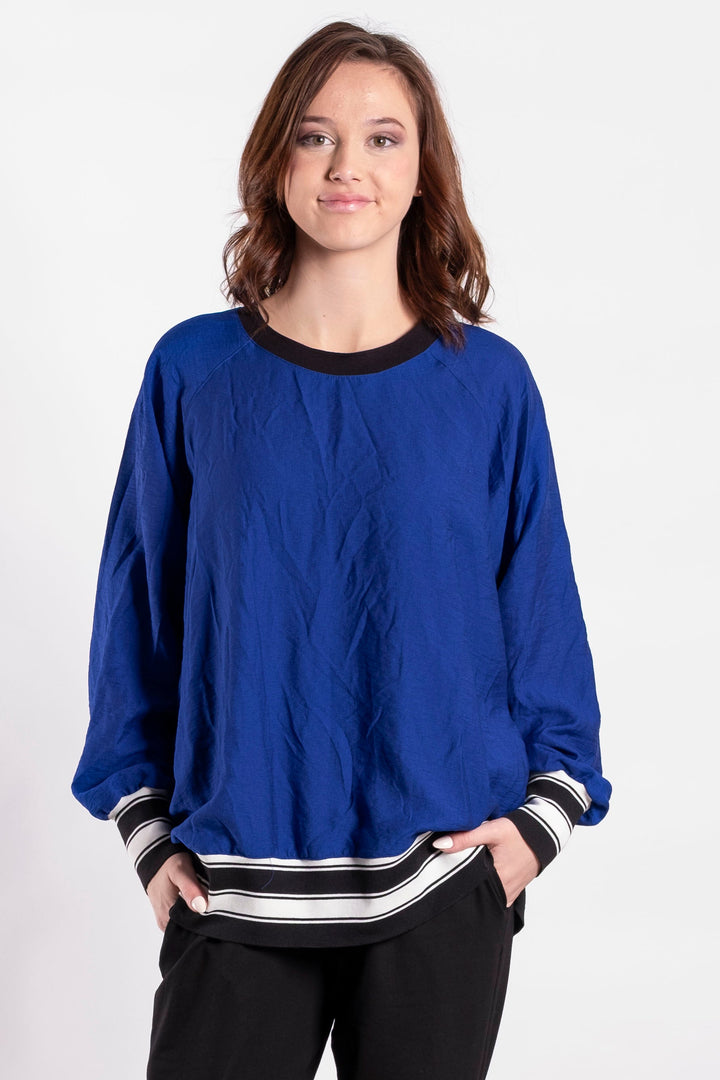 Person wearing a blue sweater and black pants on a white background