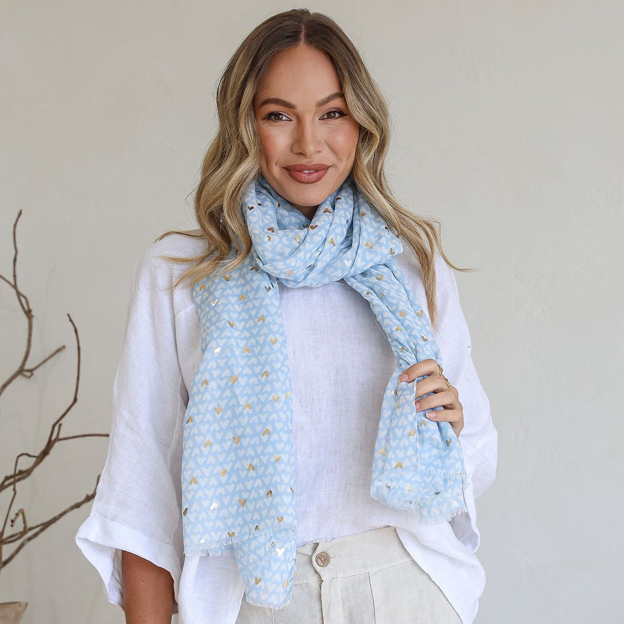 Woman wearing a light blue patterned scarf in a minimal indoor setting