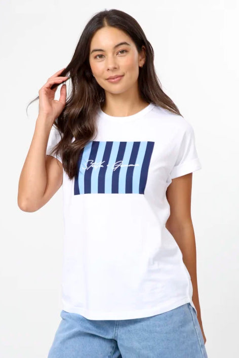 A woman modeling a white short-sleeve t-shirt with a blue striped graphic on the chest, paired with light-wash denim shorts, against a plain white studio background.