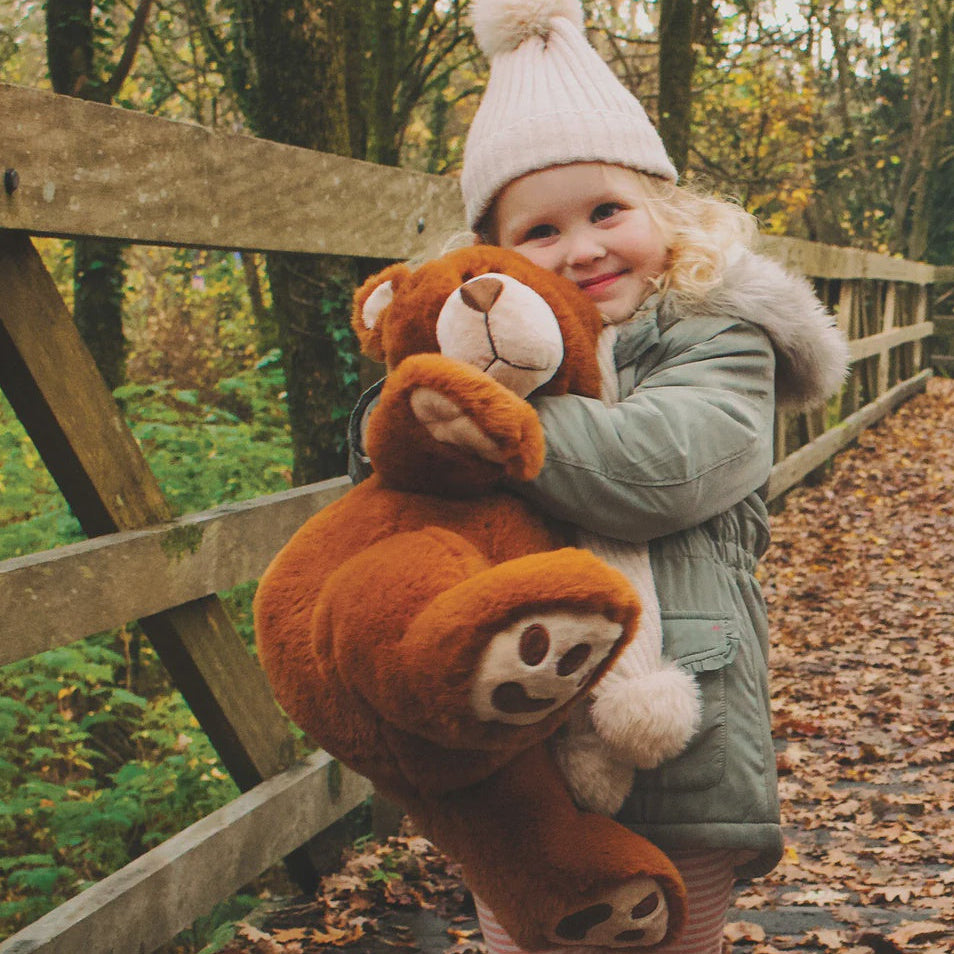 Child holding a teddy bear in an autumn forest setting