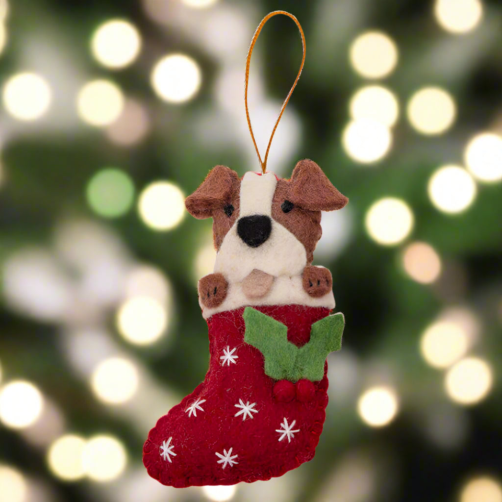 Felt dog ornament in a red stocking with white snowflakes on a white background